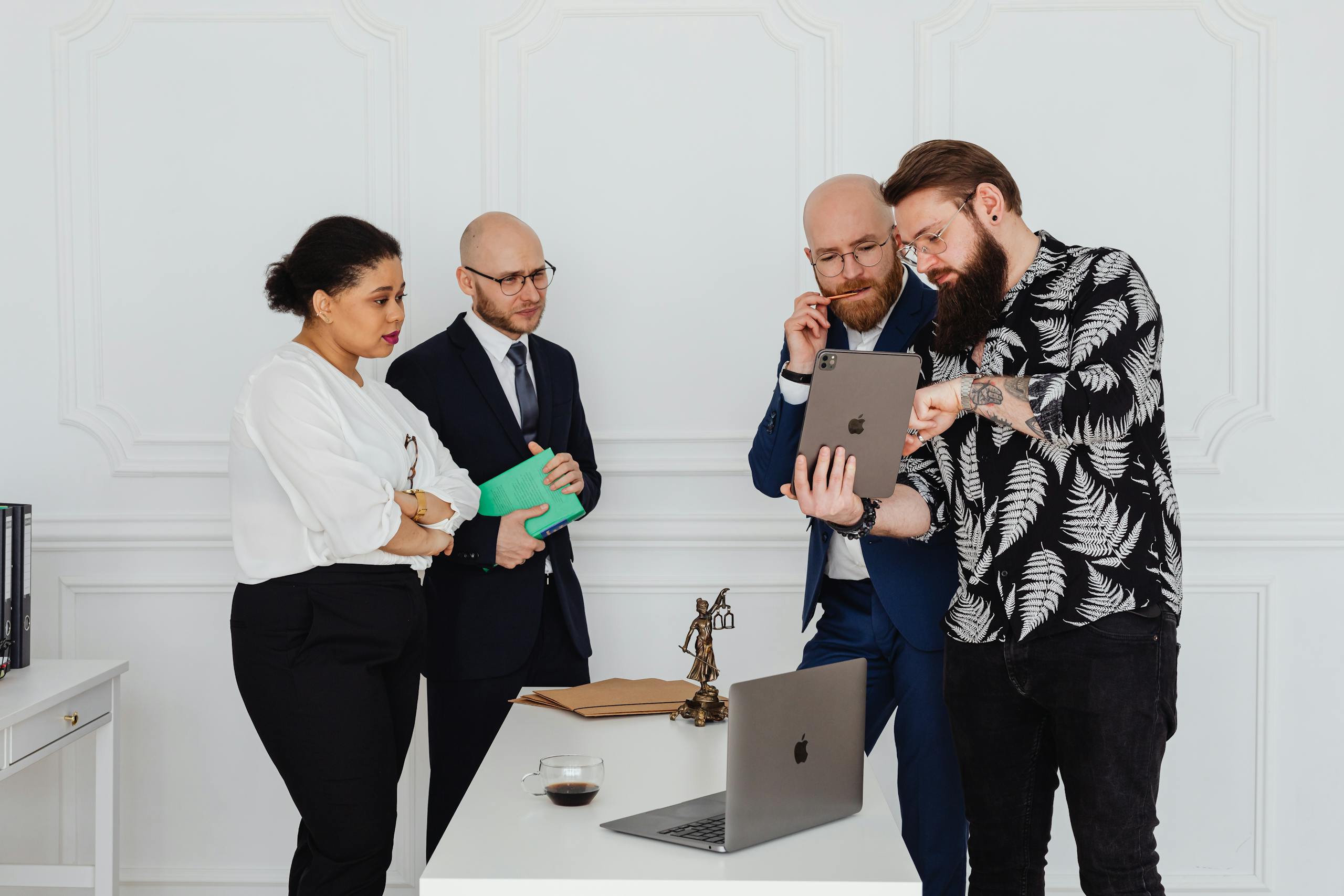 Diverse business team in a modern office discussing strategy using a tablet.